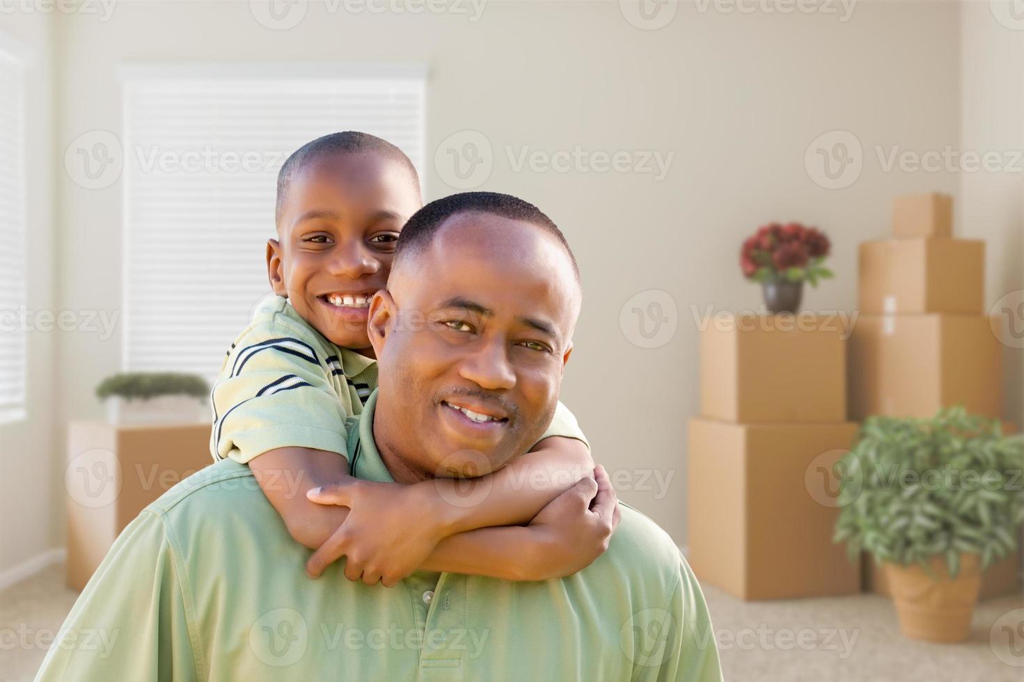 padre e hijo afroamericanos en la habitación con cajas de mudanza llenas foto