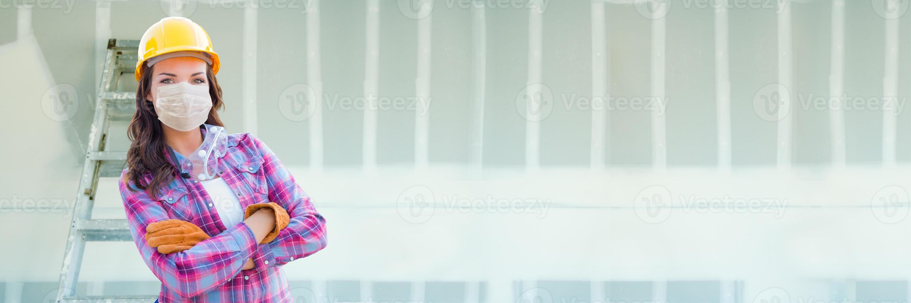 Female Contractor In Hard Hat Wearing Medical Face Mask During Coronavirus Pandemic At Construction Site Banner photo