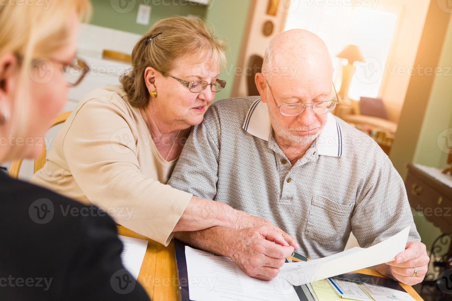 Senior Adult Couple Going Over Documents in Their Home with Agent At Signing photo