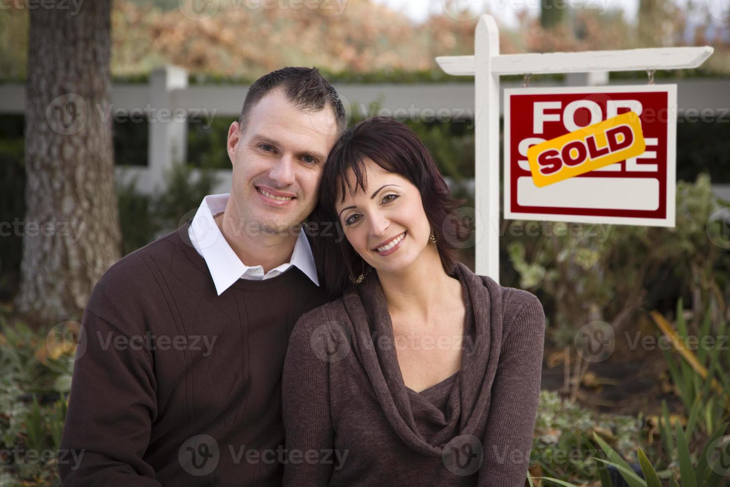 Happy Couple in Front of Sold Real Estate Sign photo