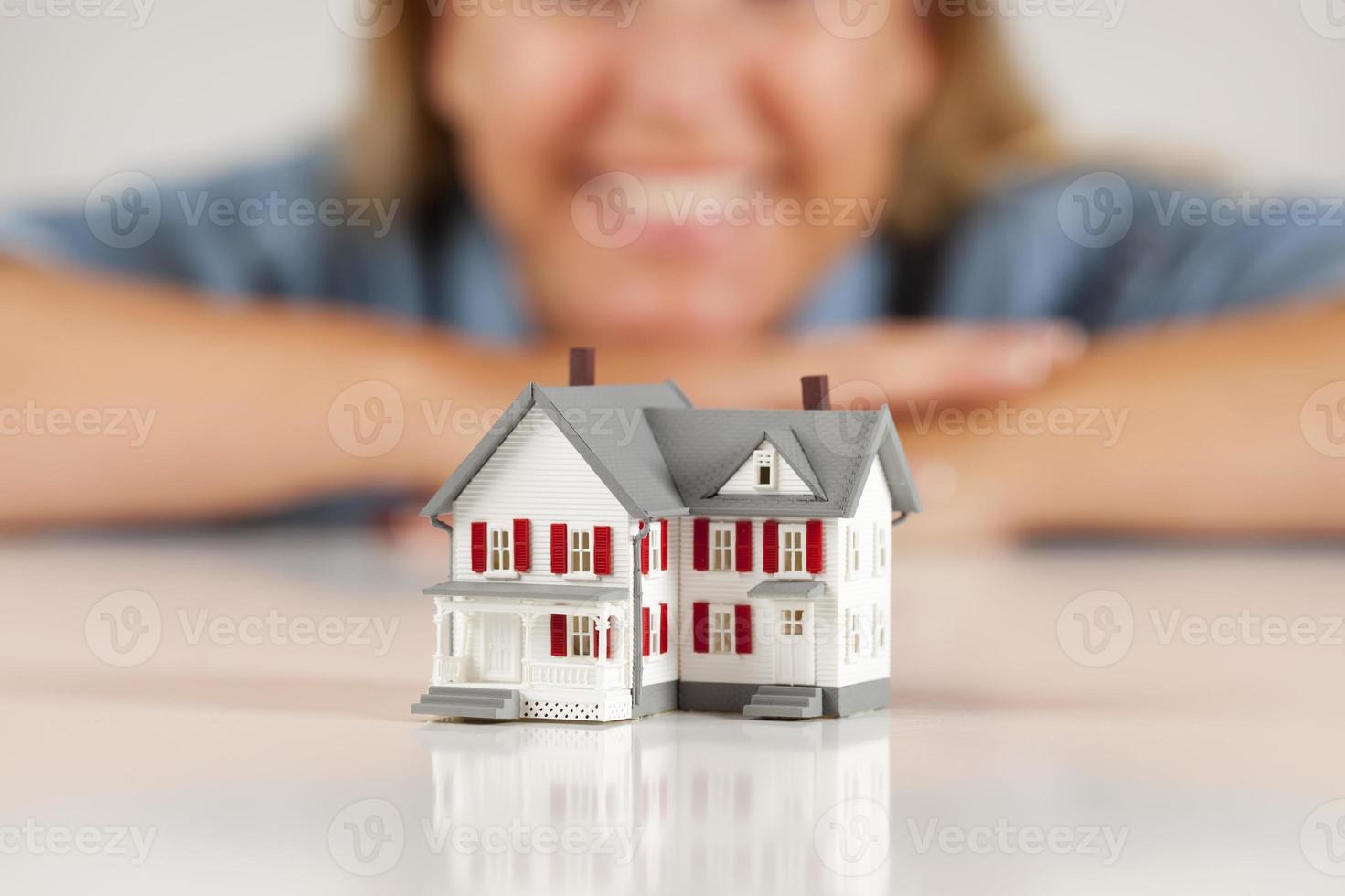 mujer sonriente detrás de la casa modelo en una superficie blanca foto