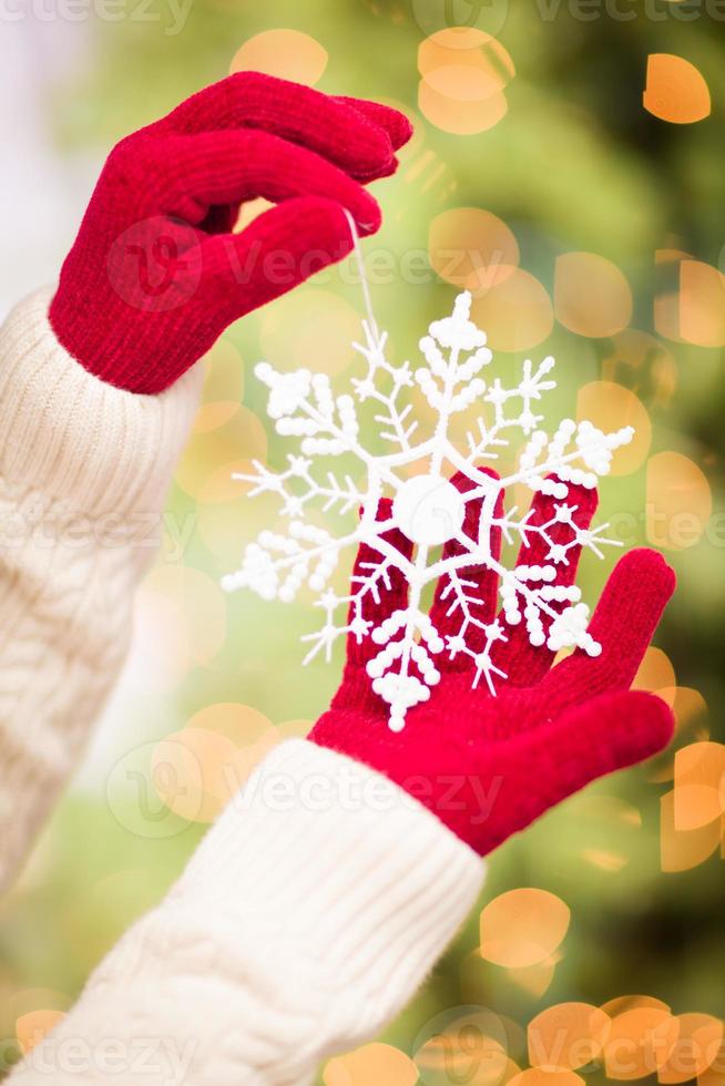 Woman Wearing Seasonal Red Mittens Holding White Snowflake Christmas Ornament photo