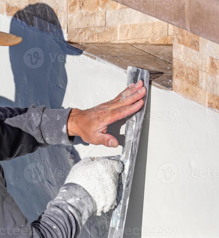 Worker Smoothing Wet Pool Plaster With Trowel photo