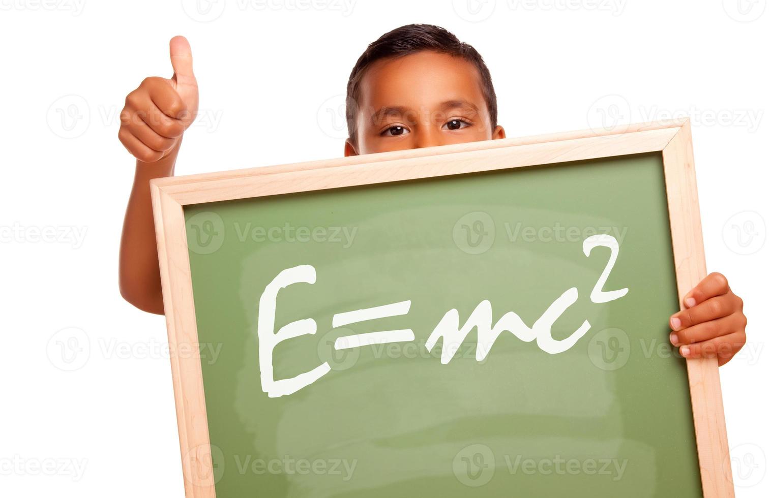 orgulloso niño hispano sosteniendo pizarra con la teoría de la relatividad foto