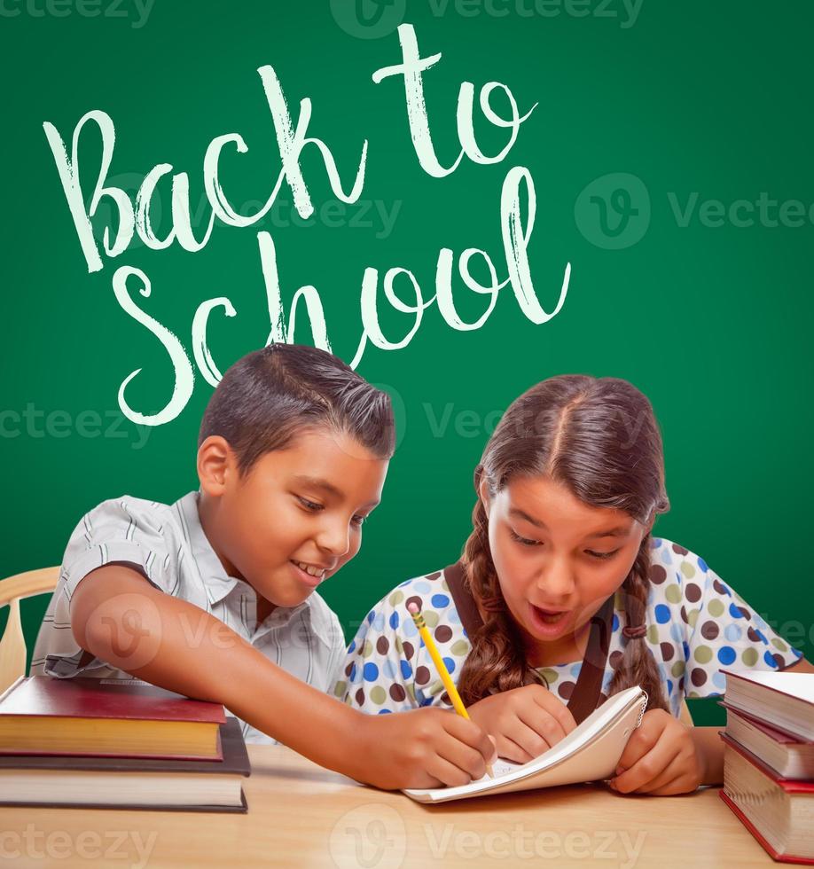 regreso a la escuela escrito en una pizarra detrás de un niño y una niña hispanos divirtiéndose estudiando juntos foto