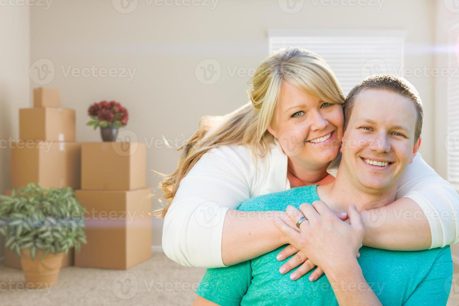 Happy Caucasian Couple Inside Empty Room with Cardboard Boxes - Moving Into New House photo