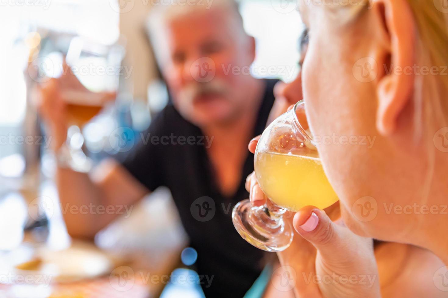 Female Sipping Glass of Micro Brew Beer At Bar With Friends photo