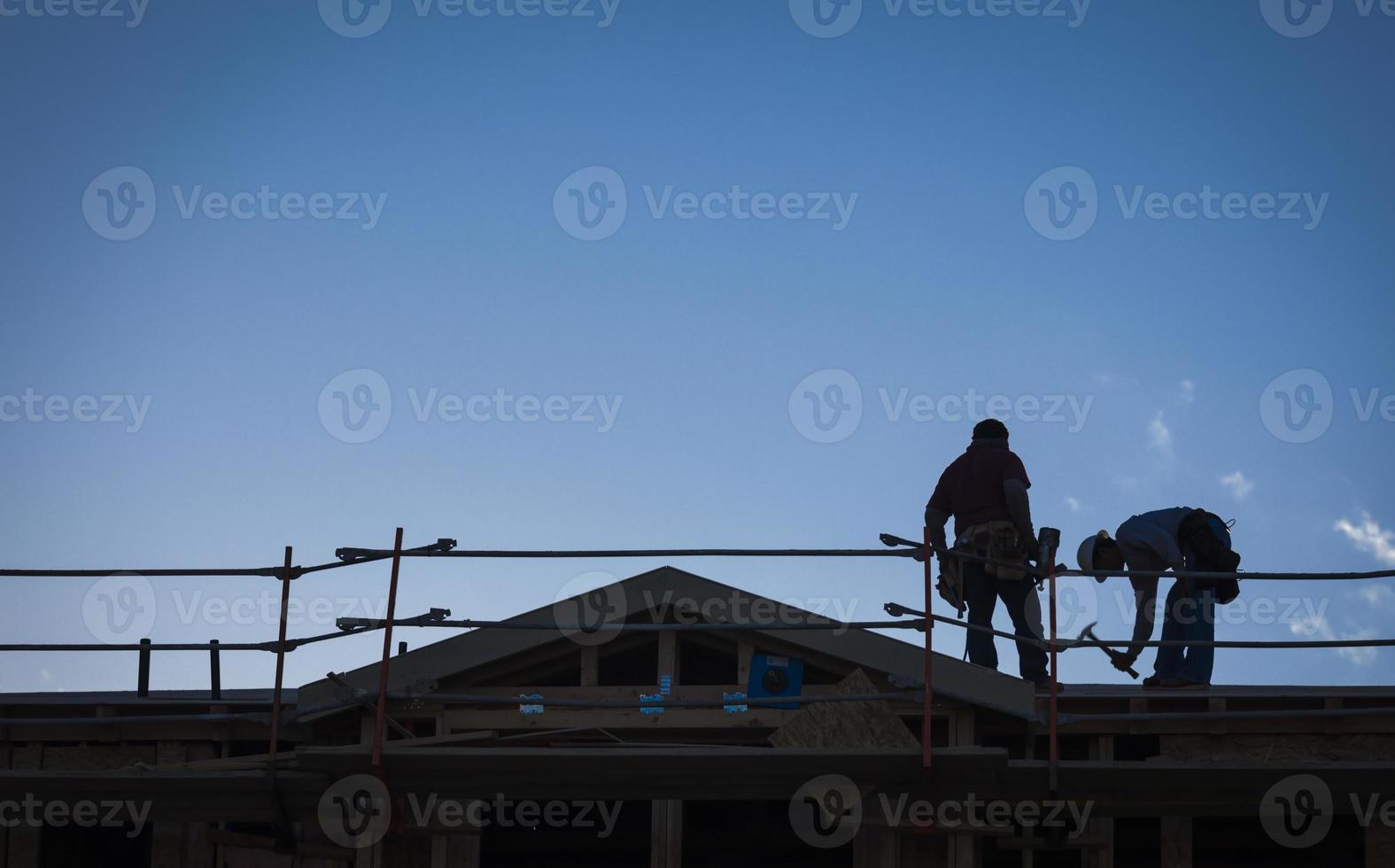 Construction Workers Silhouette on Roof photo