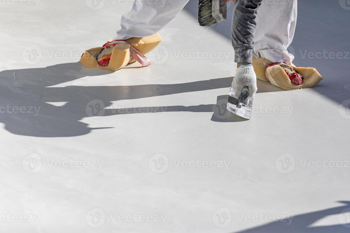 trabajador usando esponjas en los zapatos alisando el yeso húmedo de la piscina con una paleta foto