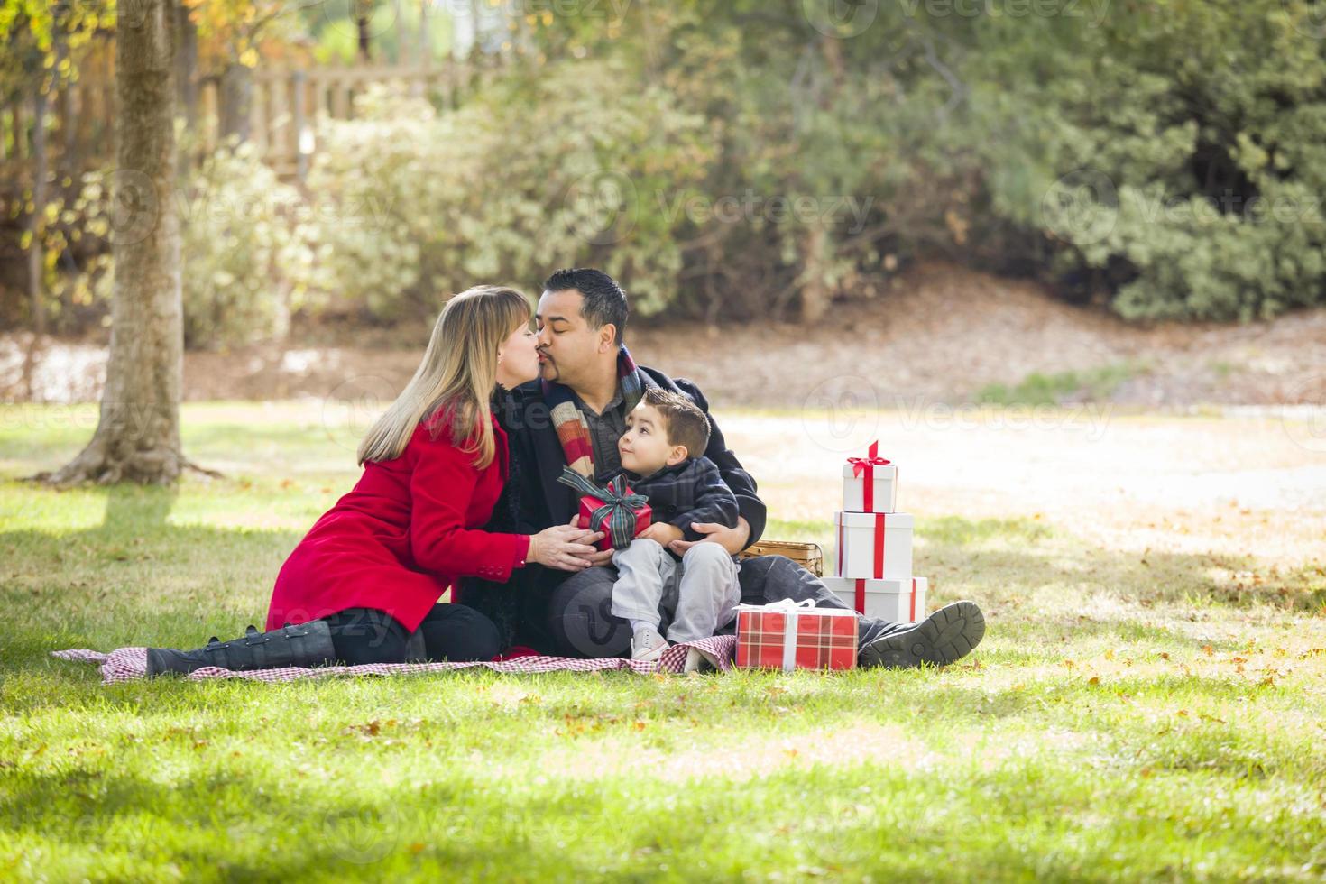 Mixed Race Family Enjoying Christmas Gifts in the Park Together photo