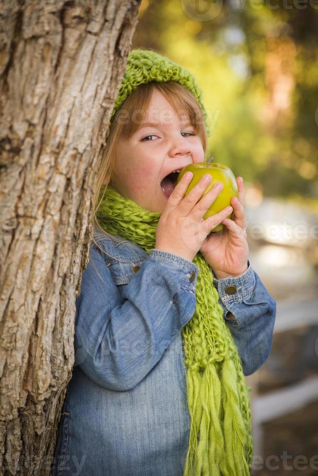 Young Girl Wearing Green Scarf and Hat Eating Apple Outside photo