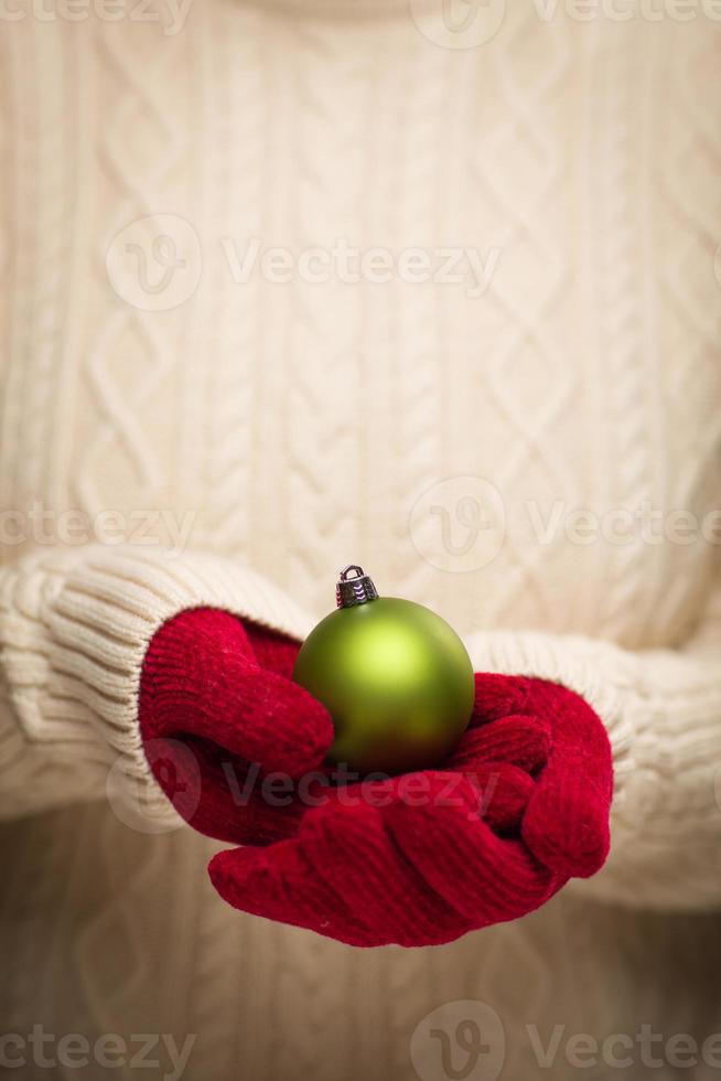 Woman Wearing Seasonal Red Mittens Holding Green Christmas Ornament photo