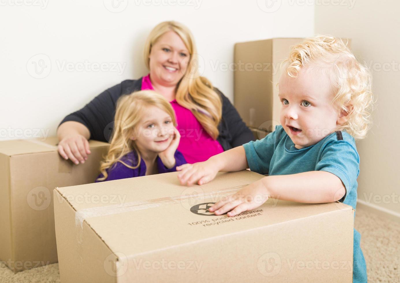 familia joven en una habitación vacía jugando con cajas móviles foto