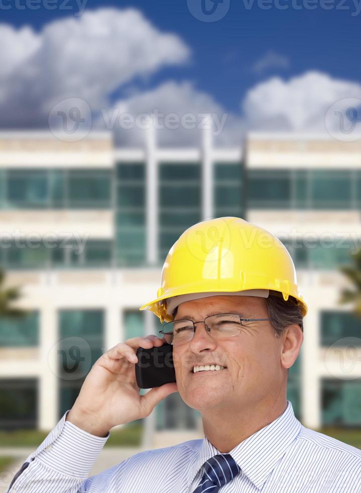 Contractor in Hardhat Talks on Phone In Front of Building photo