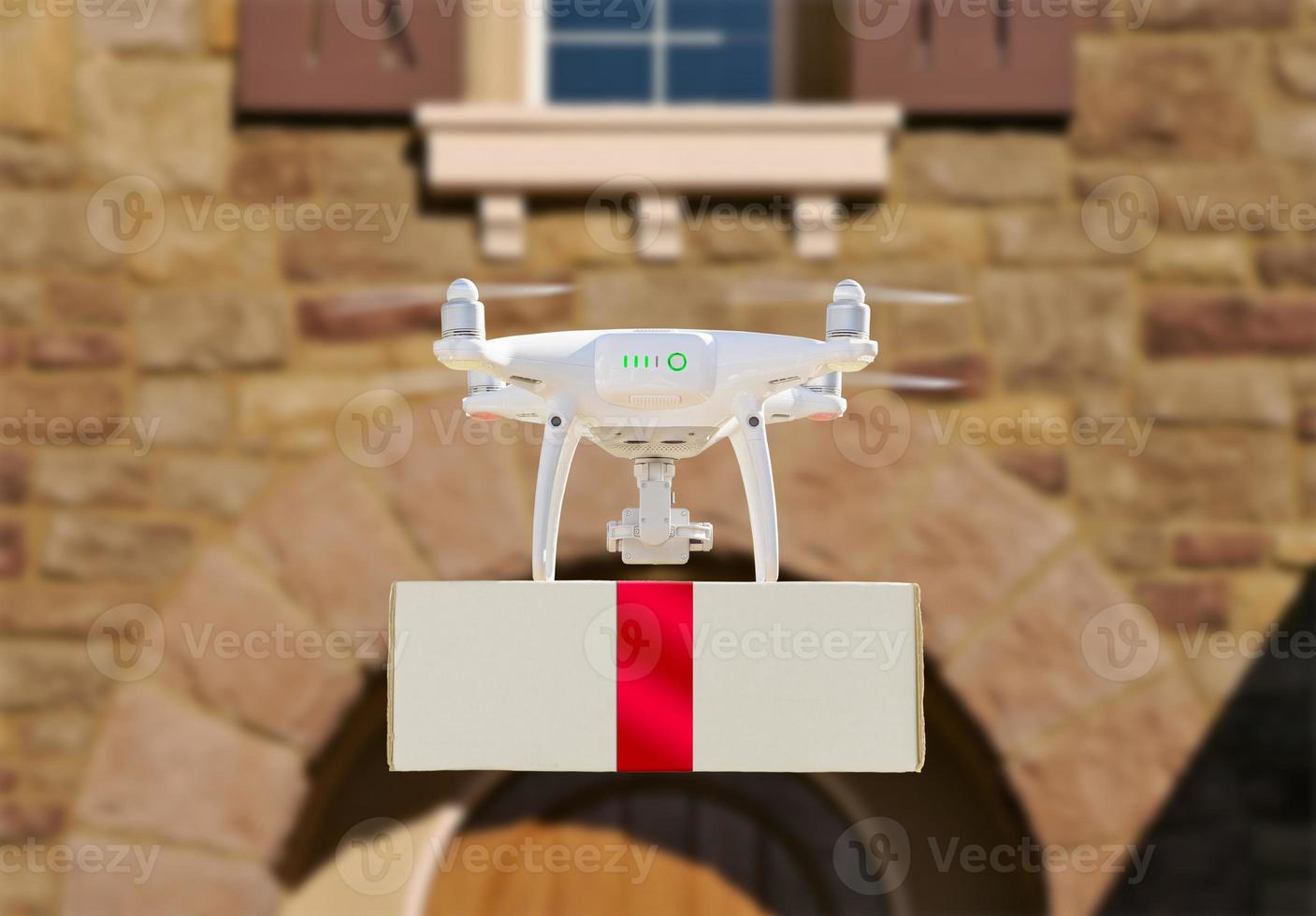Drone Delivering Red Ribbon Wrapped Package to House Porch photo