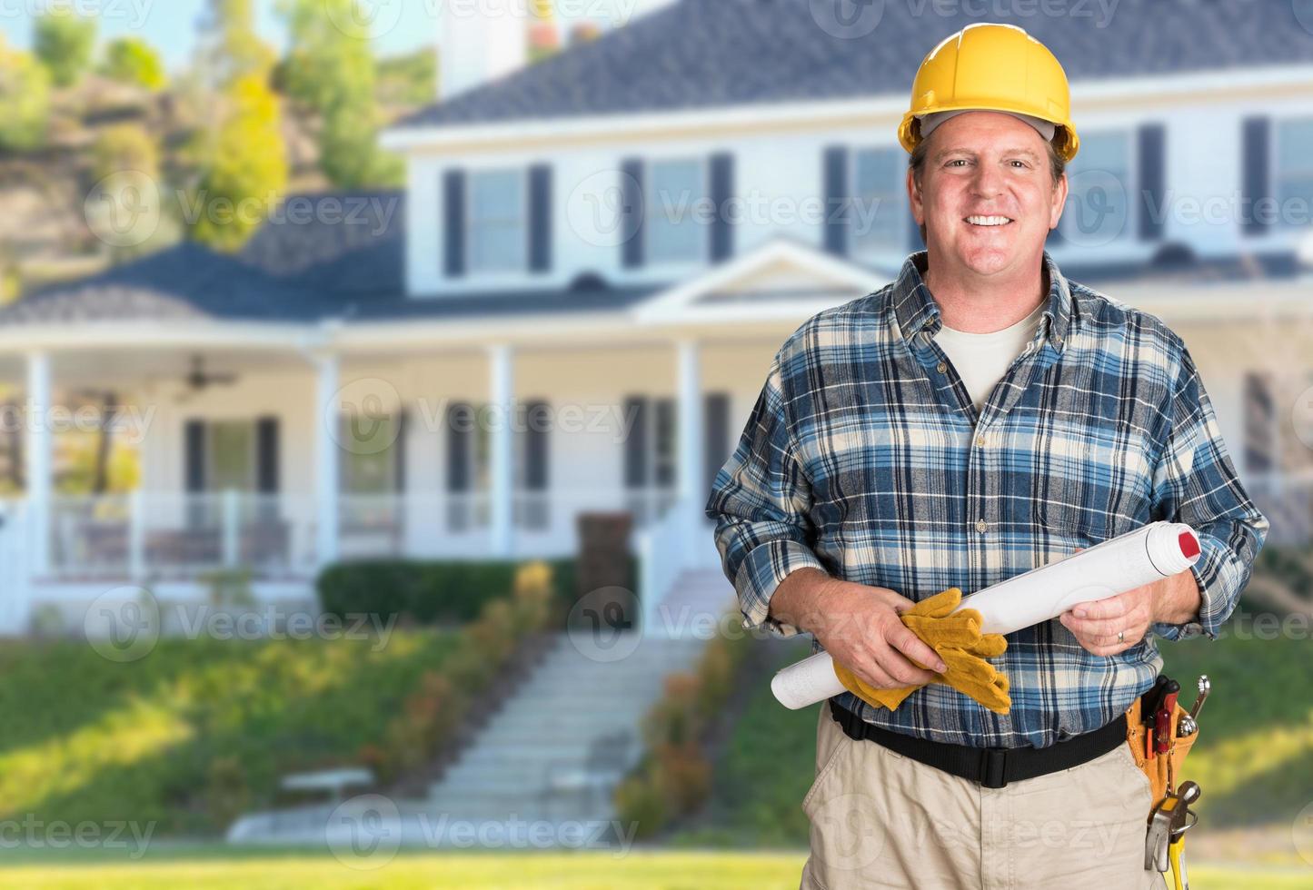 Contractor With Plans and Hard Hat In Front of Beautiful Custom House. photo