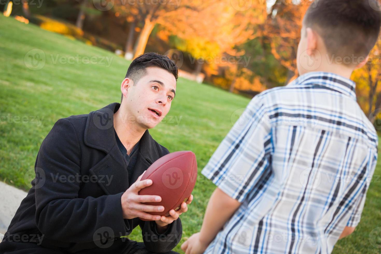 Hispanic Father Holding Football Teaching Young Boy photo
