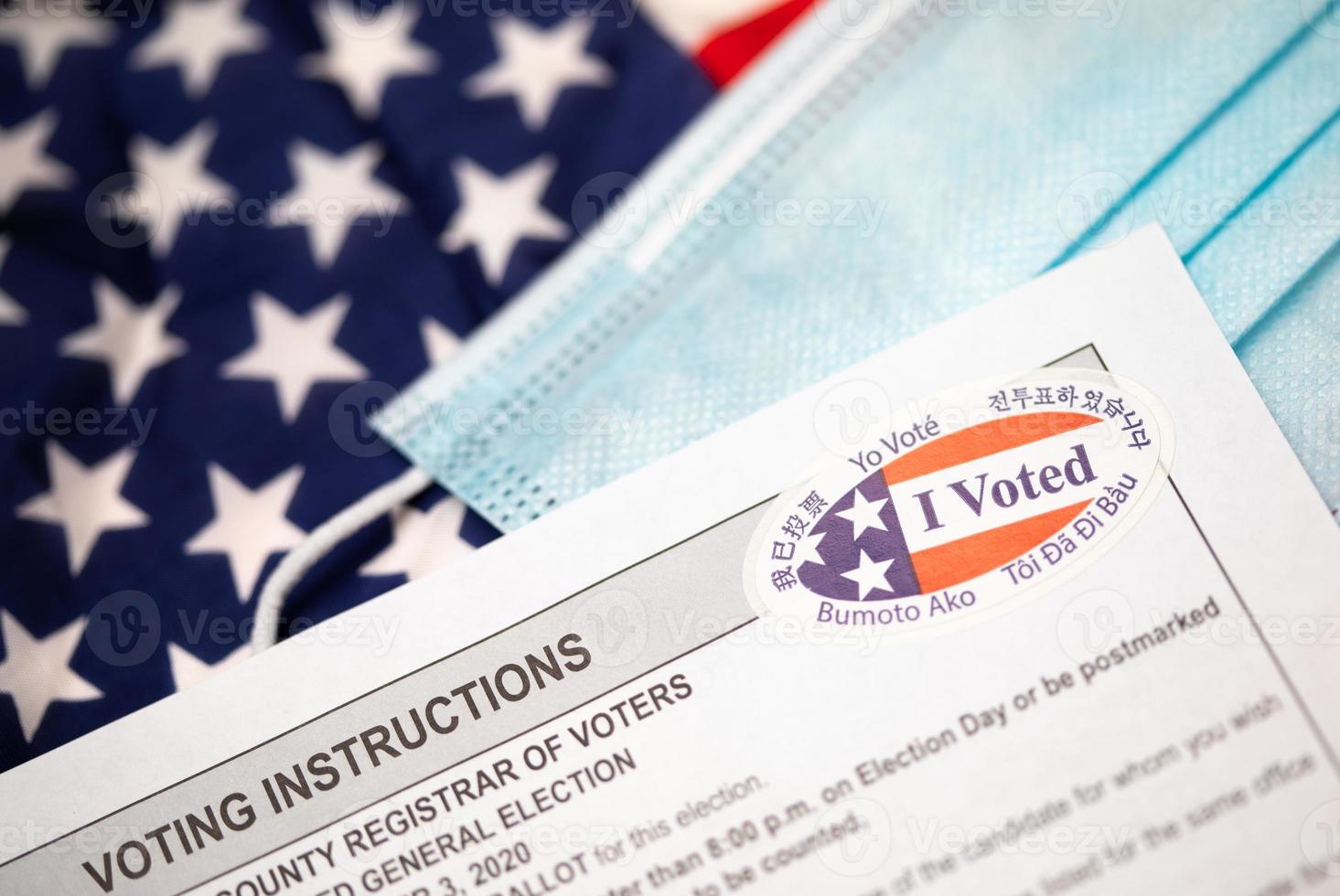 Voting Instructions and I Voted Sticker On Medical Face Mask Laying on American Flag photo