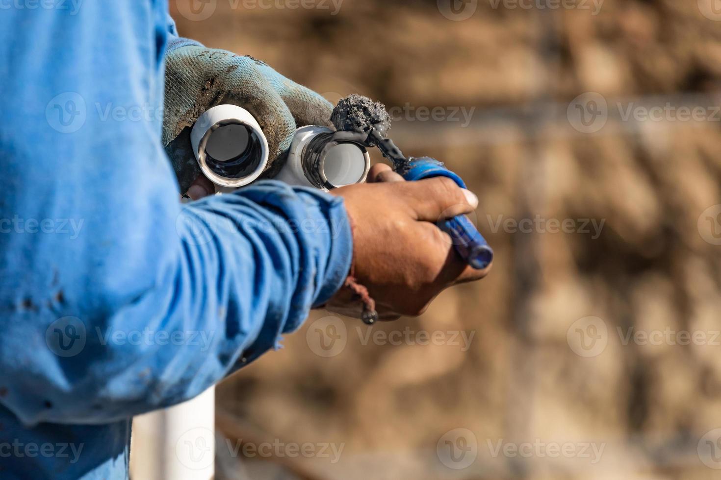 Plumber Applying Pipe Cleaner, Primer and Glue to PVC Pipe At Construction Site 16379064 Stock