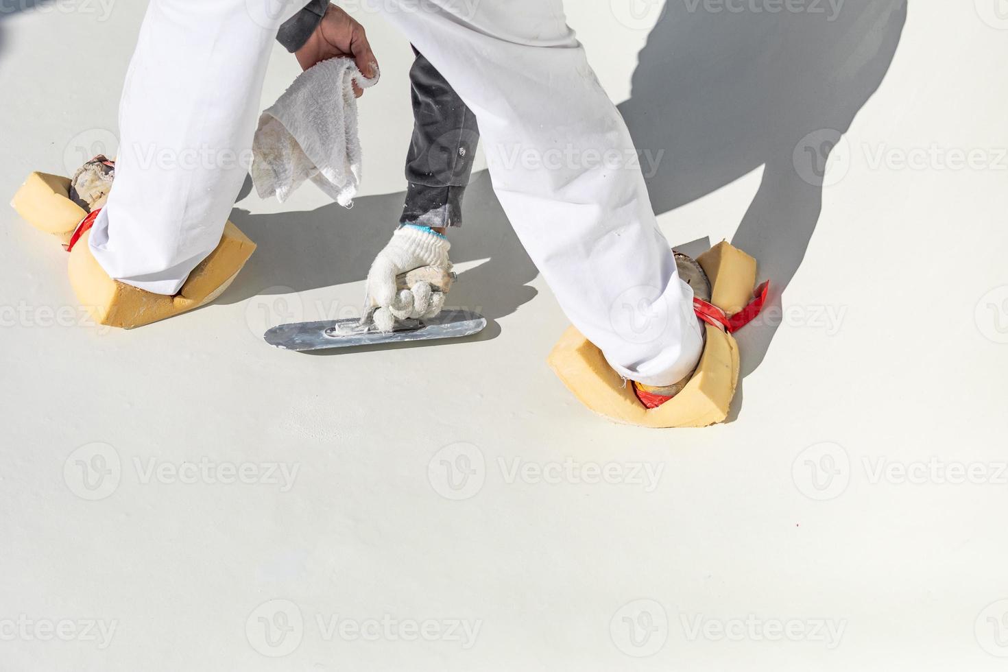 Worker Wearing Sponges On Shoes Smoothing Wet Pool Plaster With Trowel photo