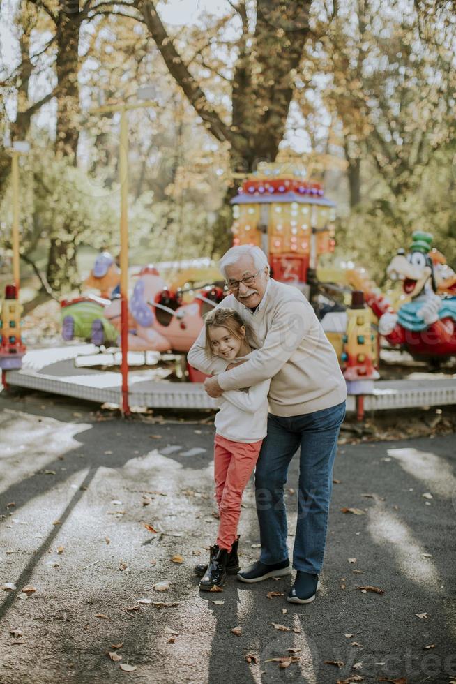 abuelo divirtiéndose con su nieta en el parque de atracciones foto