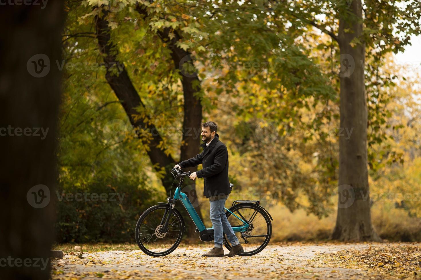 joven con bicicleta eléctrica en el parque de otoño foto