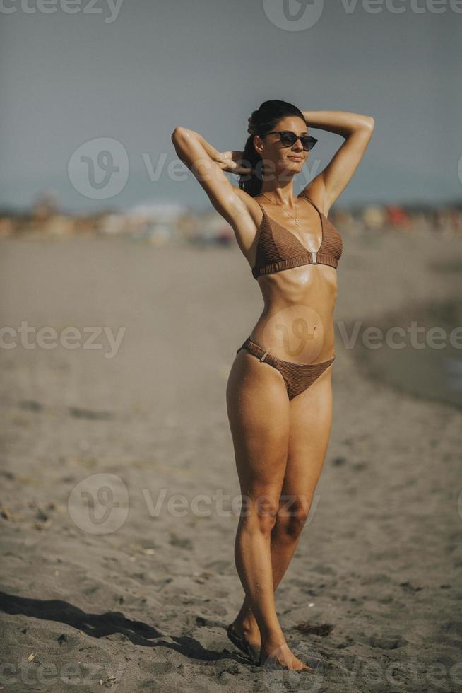 mujer joven en bikini de pie junto al mar en un día de verano foto