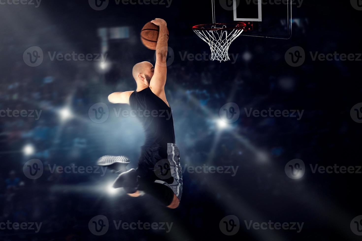 Basketball player jumping to the ring and makes slam dunk photo