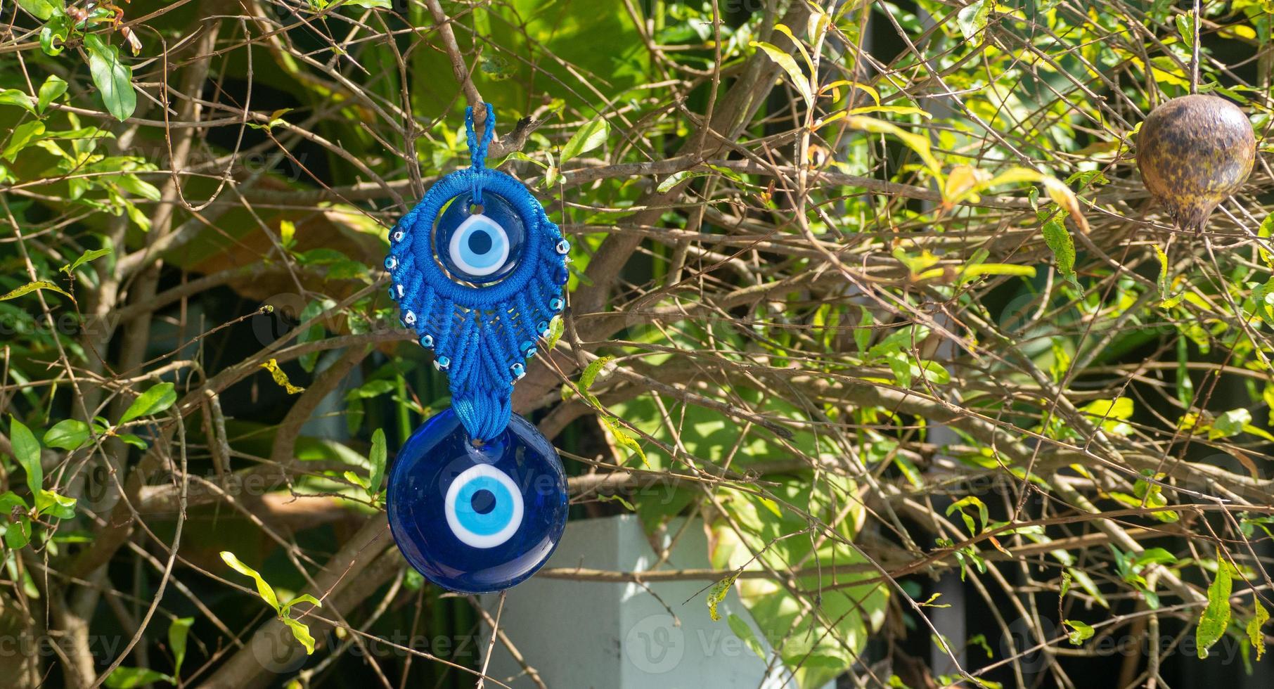 Close up of evil eye charms hang from a tree. photo