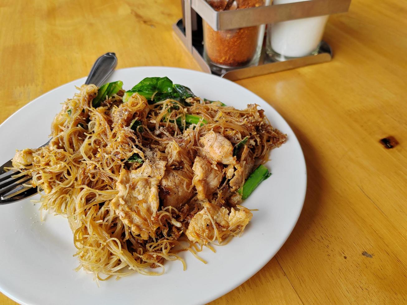 Fideos de fideos de arroz salteados con salsa de soja negra sobre una mesa de madera. comida tailandesa popular foto