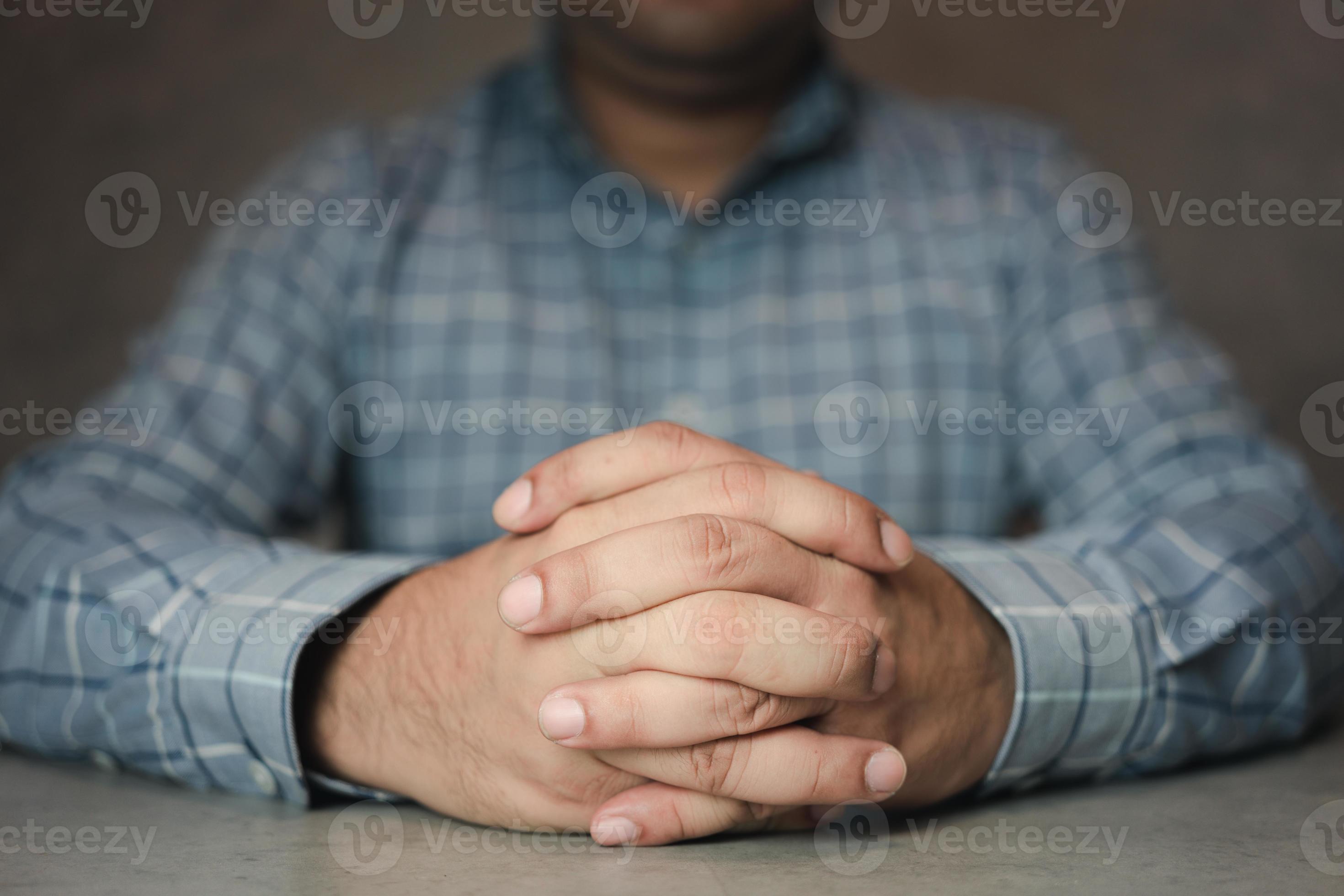 Close up of male clasped hands clenched together on table. 16391331