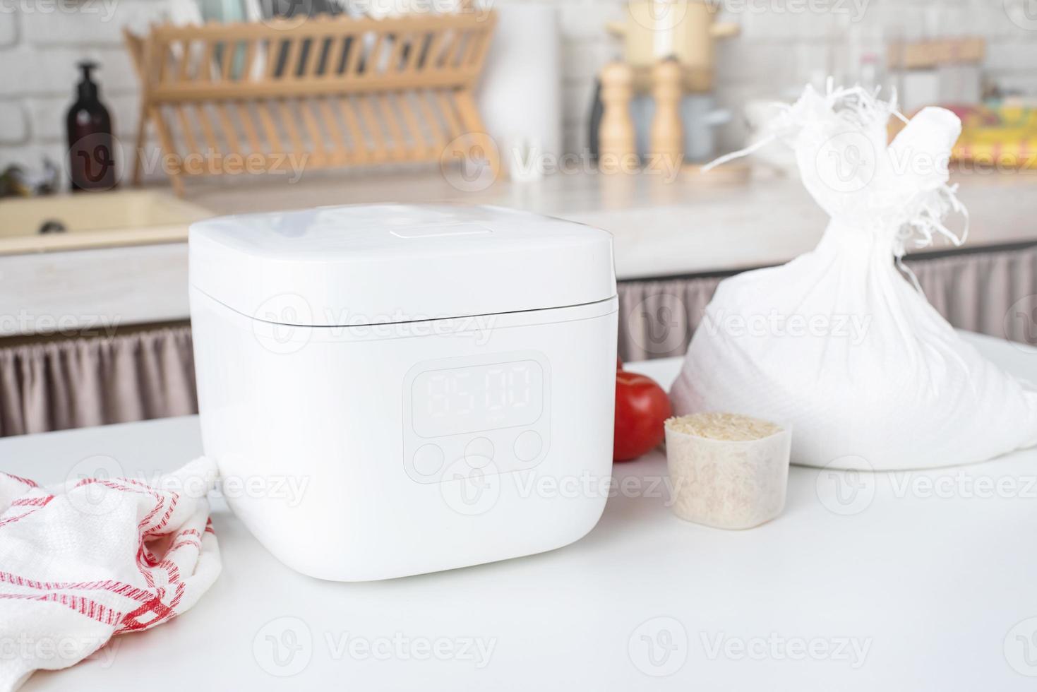 Electric rice cooker on wooden counter-top in the kitchen photo