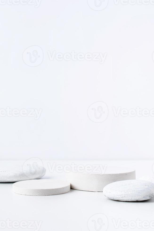 A minimalistic scene of white gypsum podium with stones on white background, for natural cosmetics photo