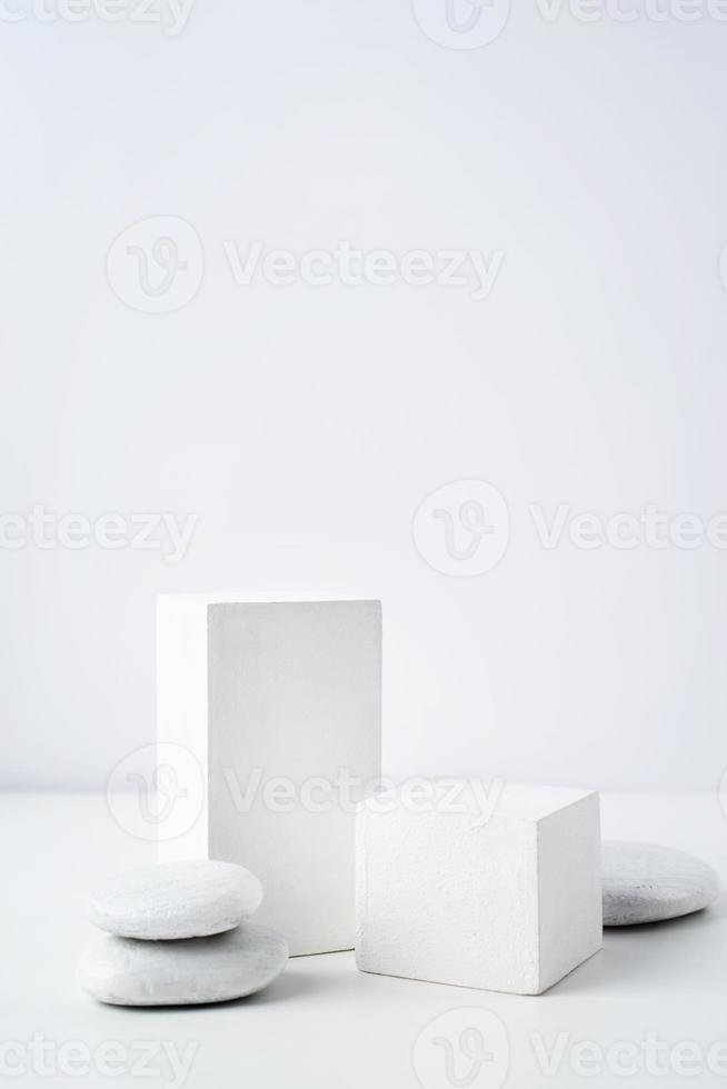 A minimalistic scene of a gypsum podium with stones on white background, for natural cosmetics photo