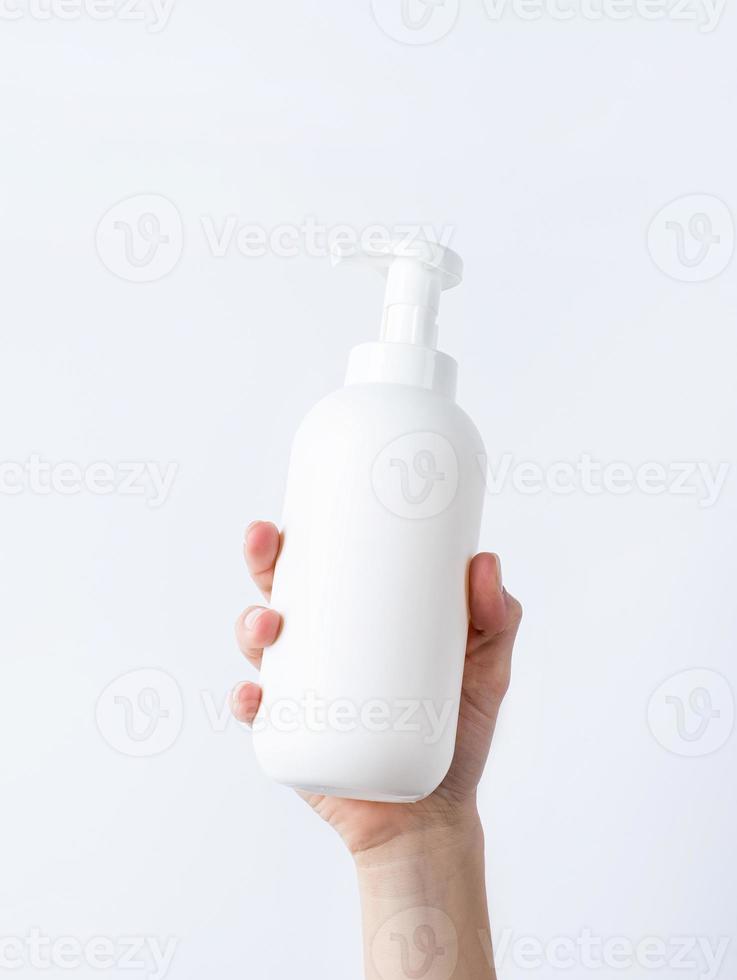 Woman hand holding blank white plastic container in light gray background photo