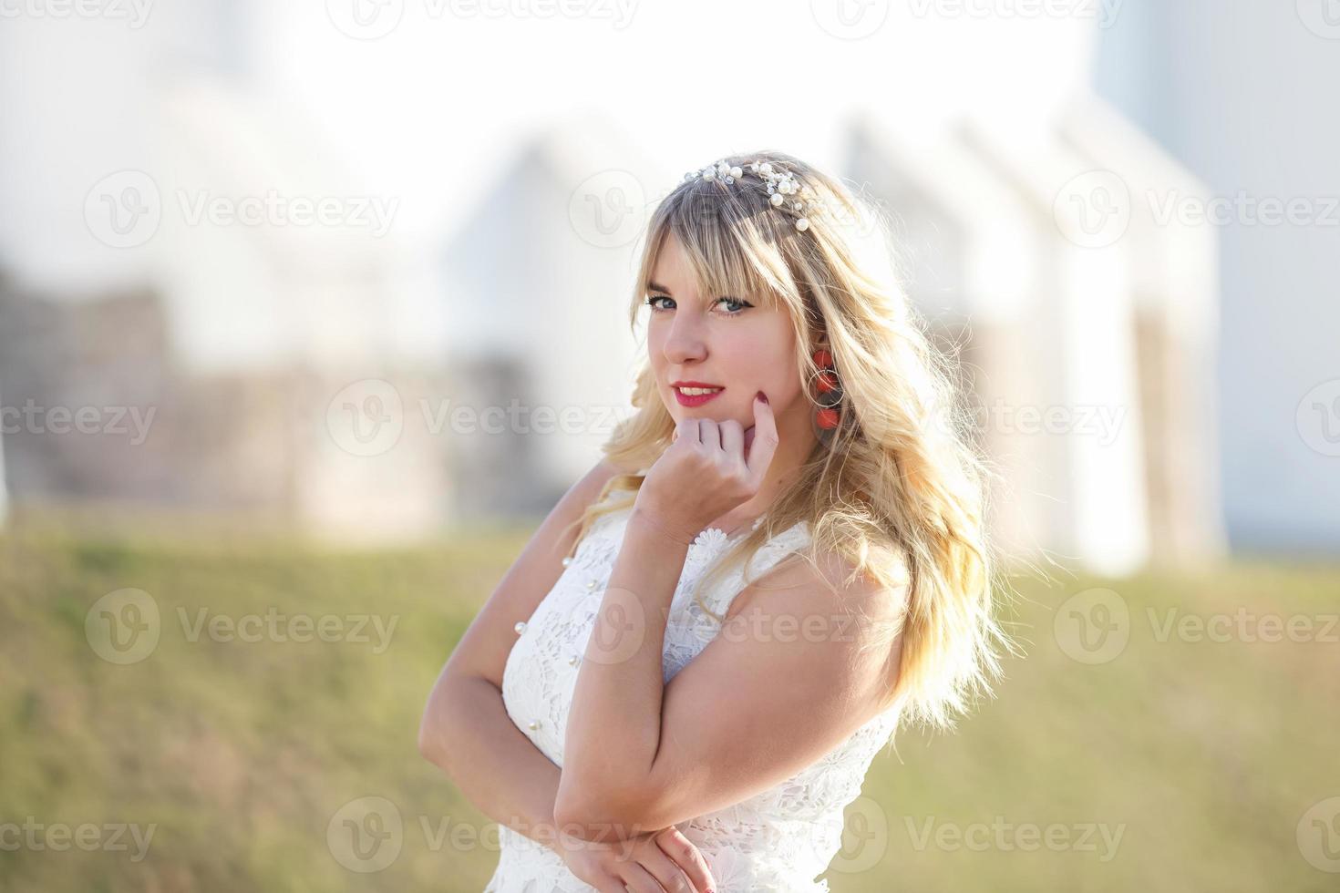 Outdoor close up portrait beautiful blonde girl with youth and skin care attractive looking at camera in white dress. Light key photo