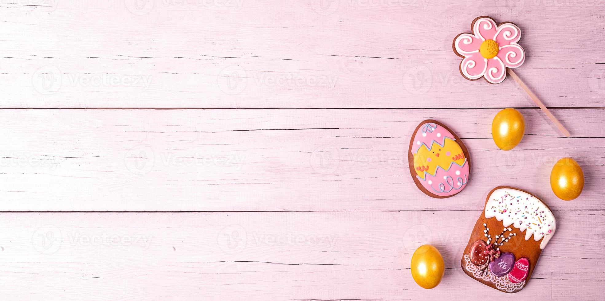 pancarta festiva de pascua. huevos amarillos y panes de jengibre coloridos sobre una mesa de madera rosa. copie el espacio. foto