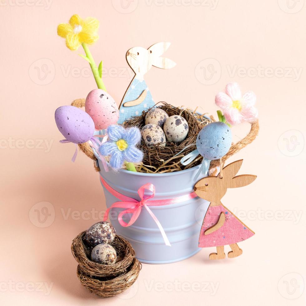 idea de decoración para niños de pascua: cubo pequeño, nidos de huevos de codorniz, huevos decorativos, flores, conejitos. foto
