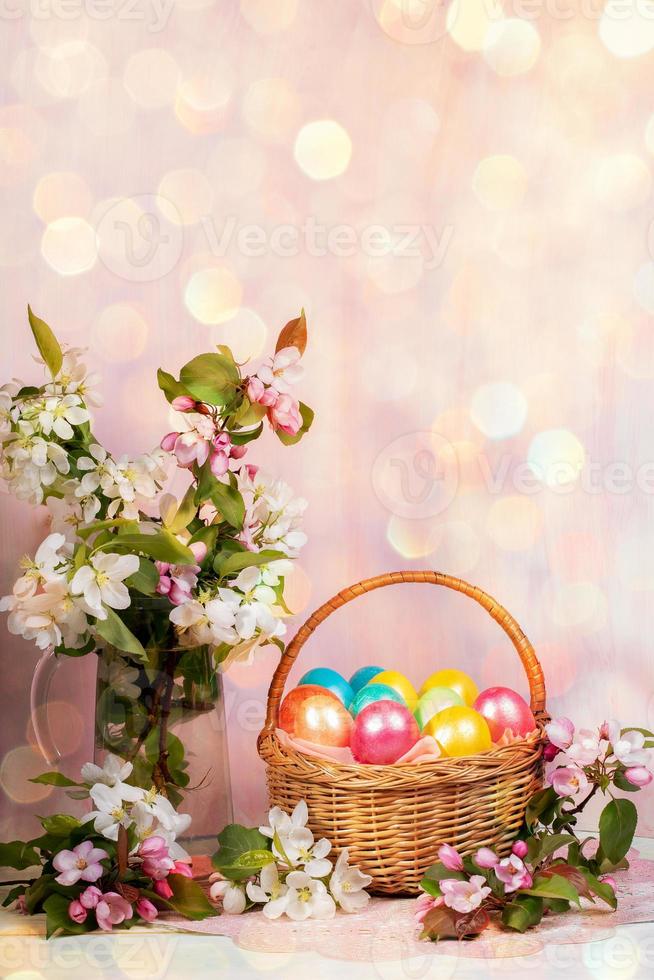 Easter composition of basket of painted Easter eggs, Apple tree twigs with background with hexagonal bokeh. Vertical. photo