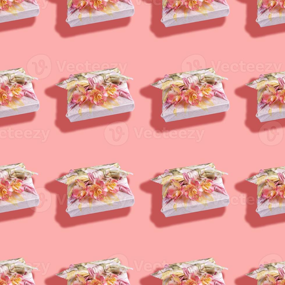 Seamless pattern of gift boxes trendy wrapped in textile in Furoshiki technique with flowers and shadows on pink. photo