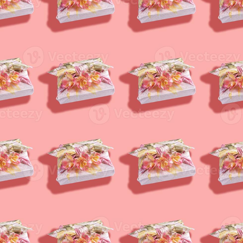 Seamless pattern of gift boxes trendy wrapped in textile in Furoshiki technique with flowers and shadows on pink. photo