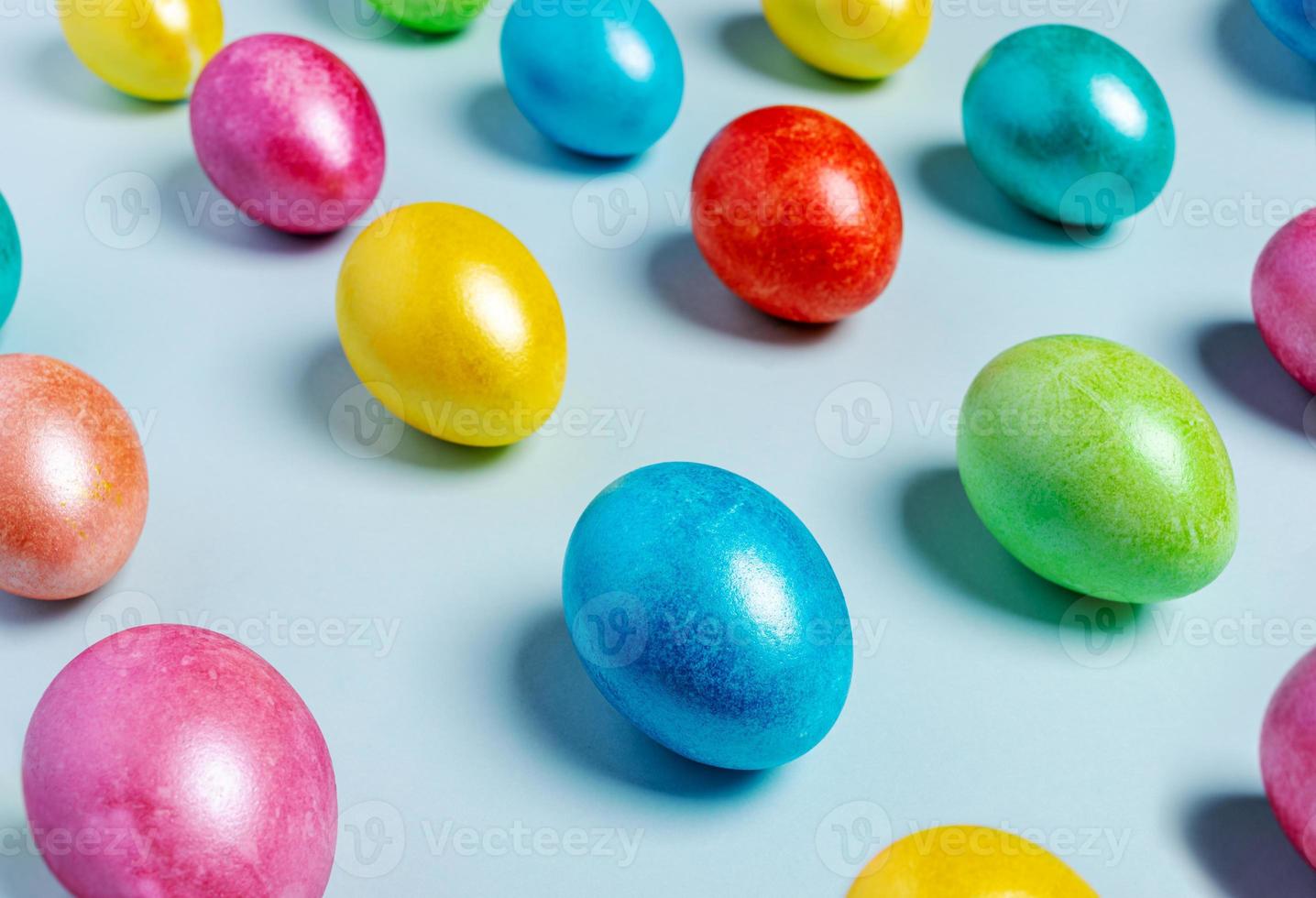 Easter creative festive composition. Diagonal lines of glossy Easter eggs on light blue pastel backdrop. Selective focus. photo
