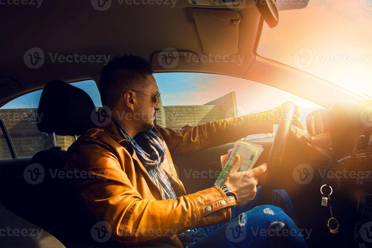 modelo de moda hombre conduciendo un coche con mucho dinero en la mano foto