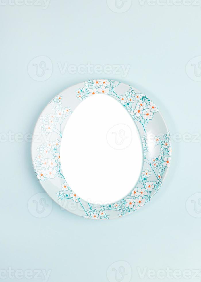 Easter creative festive minimal layout with copy space in egg shape on plate on center of light blue backdrop. photo