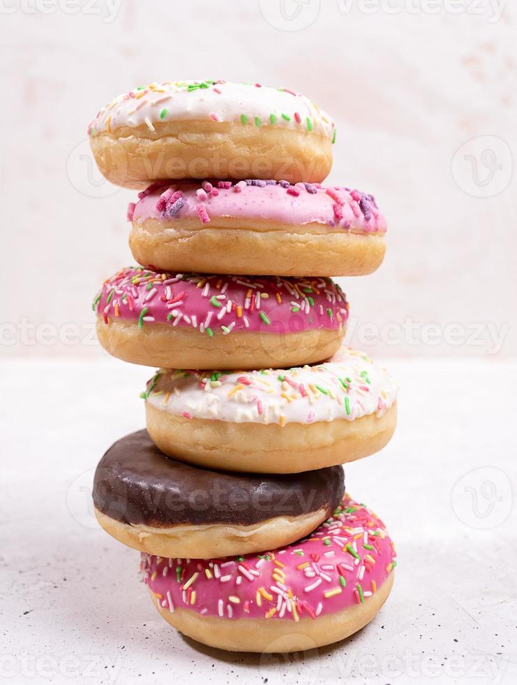 Stack of six traditional doughnuts with multicolored glaze on white background. Close-up. photo