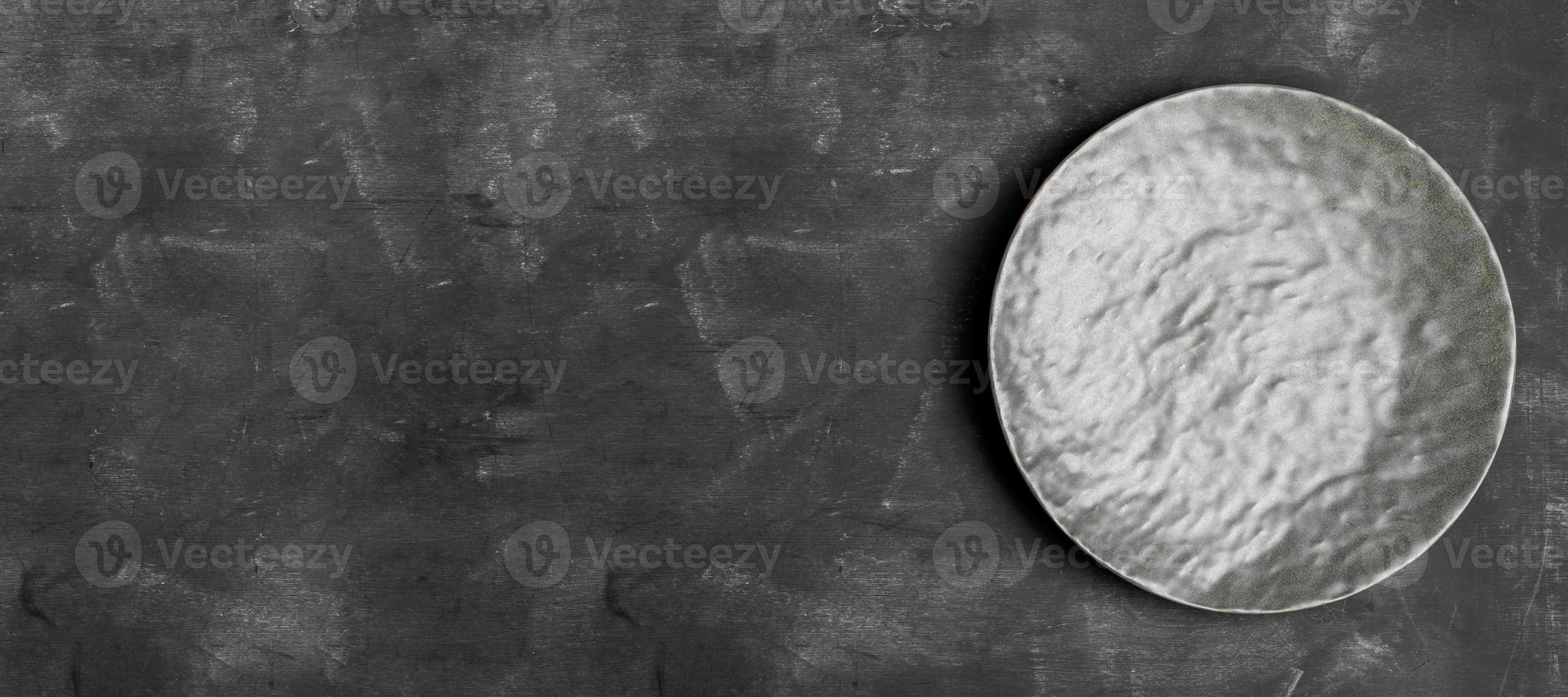 Empty grey textured plate on dark grey wooden backdrop. Minimal image. Banner. Top view. Copy space. photo