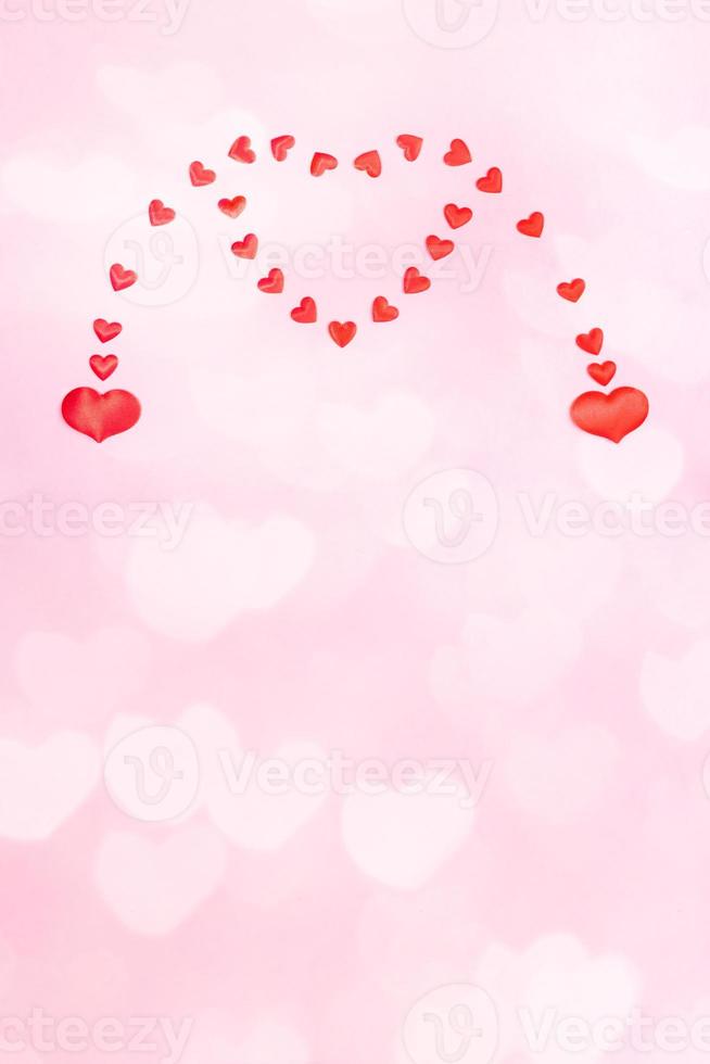 Valentines day or wedding vertical festive pink background with hearts bokeh. Two small hearts merging to one big heart. photo