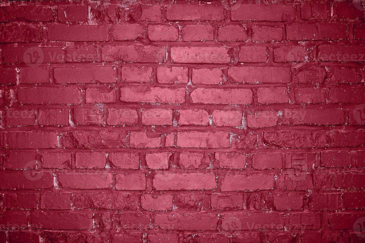 Grunge old brick wall as background toning in color 2023 Viva Magenta. photo