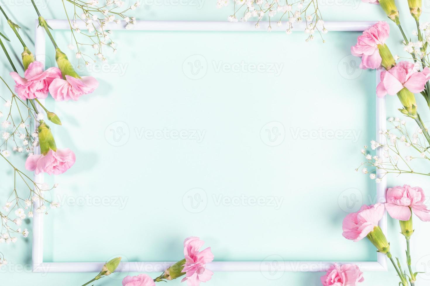 White frame with pink carnations and white gypsophila flowers on light blue. Mother's day. Mock up. photo