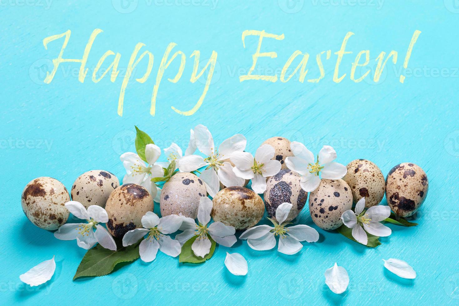 Festive Easter greeting card with quail eggs, white Apple tree flowers and words Happy Easter on turquoise background. photo